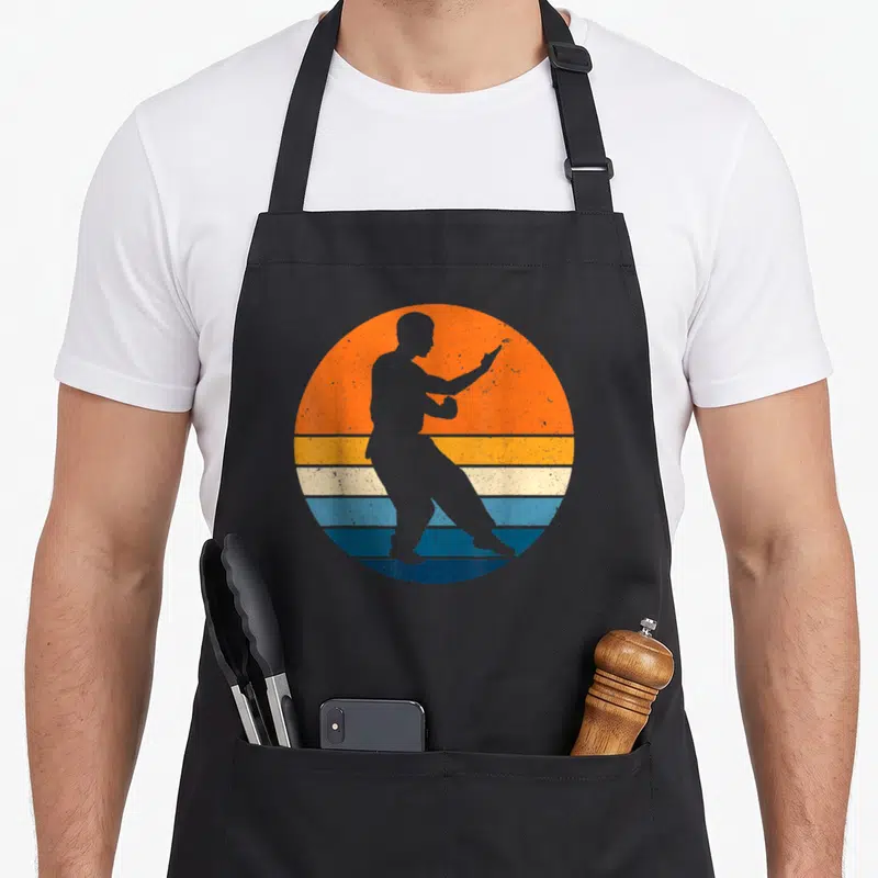 Tablier de cuisine noir avec silhouette Wing Chun sur fond sunset orange et bandes bleues rétro