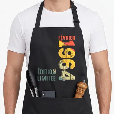 Tablier de cuisine noir avec l'inscription Février 1964 « Édition Limitée » en typographie rétro colorée et texturée.