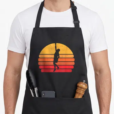 Tablier de cuisine noir avec silhouette grimpeur devant soleil rayé orange et rouge style rétro