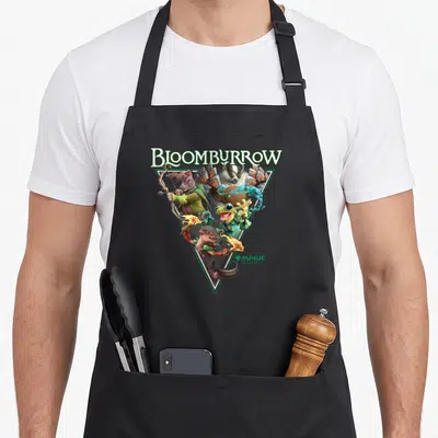 Tablier de cuisine noir avec illustration triangulaire de Bloomburrow montrant des créatures animales magiques et le logo Magic.