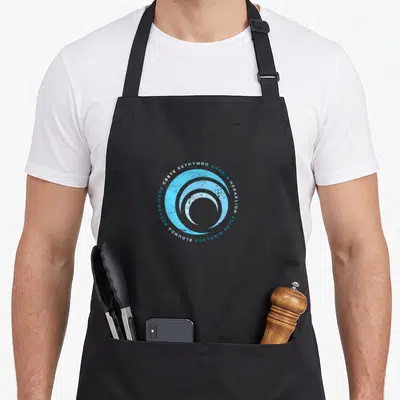 Tablier de cuisine noir avec une vague circulaire bleue et les noms Crete, Rethymno, Chania, Heraklion, Agios Nikolaos, E lournd a, Hersonissos.