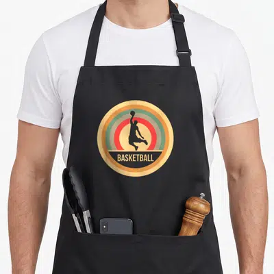 Tablier de cuisine noir avec logo circulaire rétro montrant un joueur de basket en silhouette et le mot BASKETBALL.