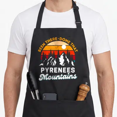 Tablier de cuisine noir avec illustration rétro des Pyrénées et texte BEEN THERE DONE THAT en arc de cercle orange et rouge.