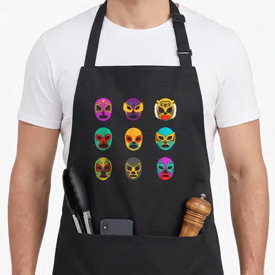 Tablier de cuisine noir avec neuf masques de lucha libre colorés disposés en grille.