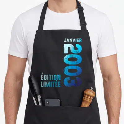 Tablier de cuisine noir avec inscription verticale « 2003 » et texte « Janvier édition limitée » en bleu dégradé.