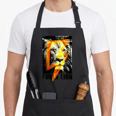 Tablier de cuisine noir avec illustration d'un visage de lion traversé par une foudre orange et le texte Furia Lion en bas.