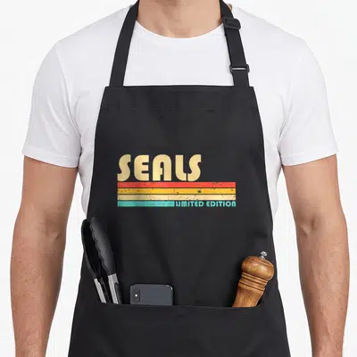 Tablier de cuisine noir avec l inscription SEALS Limited Edition et bandes colorées horizontales dans un style rétro.