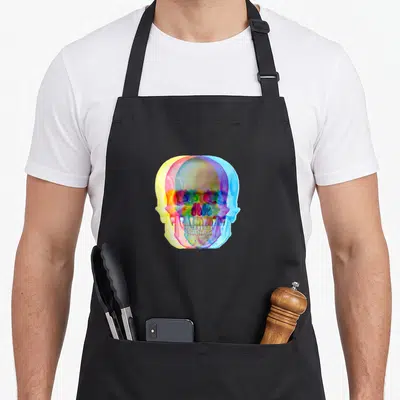 Tablier de cuisine noir avec illustration d'un crâne multicolore aux effets de superposition rétro.
