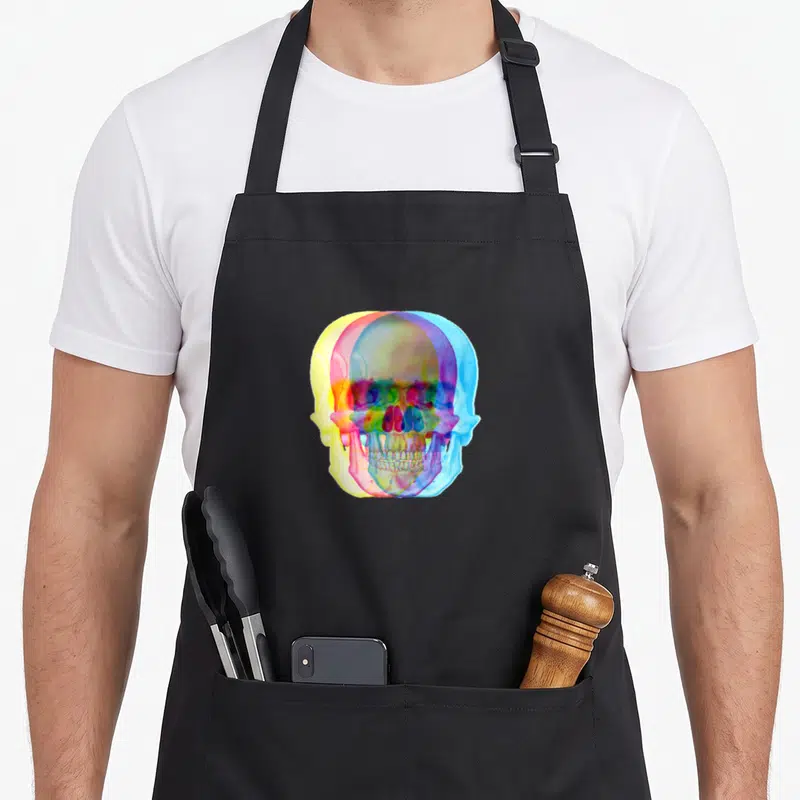 Tablier de cuisine noir avec illustration d'un crâne multicolore aux effets de superposition rétro.