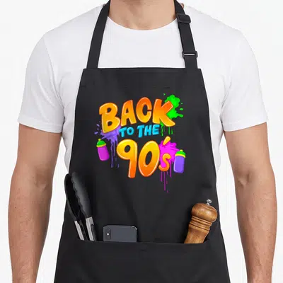 Tablier de cuisine noir avec inscription Back to the 90s et bombes de peinture colorées.