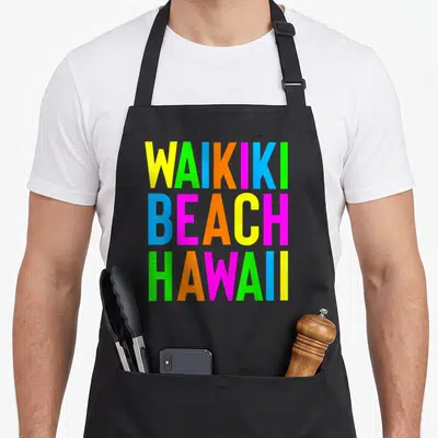 Tablier de cuisine noir avec l'inscription Waikiki Beach Hawaii en lettres colorées géométriques.