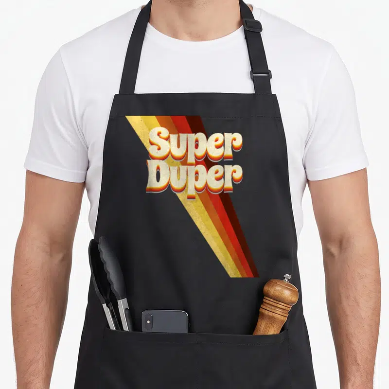 Tablier de cuisine noir avec l'inscription Super Duper en lettres capitules blanches et rayures orange jaunes retro septante