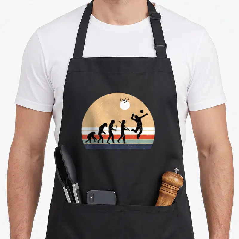 Tablier de cuisine noir avec illustration rétro montrant l'évolution humaine vers le joueur de volleyball sautant.