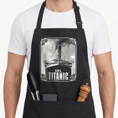 Tablier de cuisine noir avec illustration vintage du R.M.S. Titanic et cadre ornemental blanc.