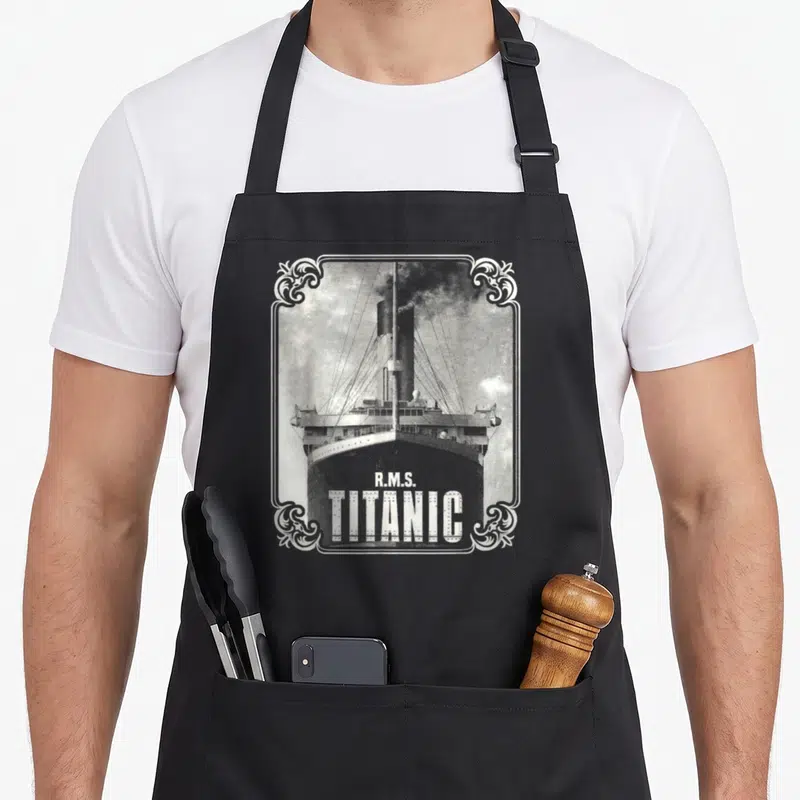 Tablier de cuisine noir avec illustration vintage du R.M.S. Titanic et cadre ornemental blanc.
