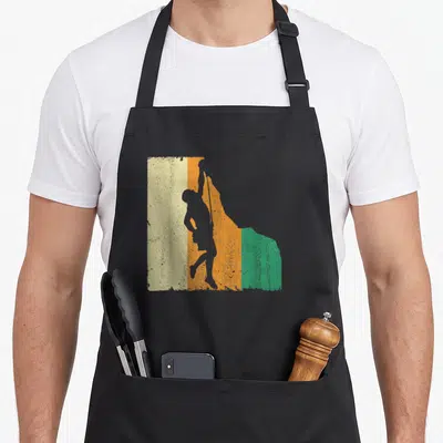 Tablier de cuisine noir avec une illustration rétro d'un escaladeur sur fond de bandes orange vert et crème.