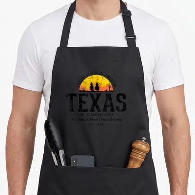 Tablier de cuisine noir avec illustration rétro Texas cow-boys et texteUnited States of America en arc de cercle.