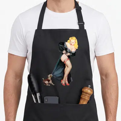 Tablier de cuisine noir avec illustration d'une pin-up blonde en robe noire tirée par un petit chien aux couleurs vives.