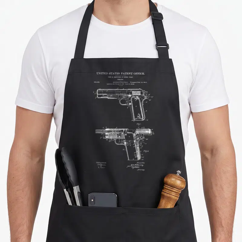 Tablier de cuisine noir avec un schéma blanc de brevet de pistolet 45ACP en style vintage.