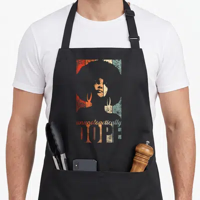 Tablier de cuisine noir avec illustration femme afro et texte unapologetically HOPE en orange et turquoise.