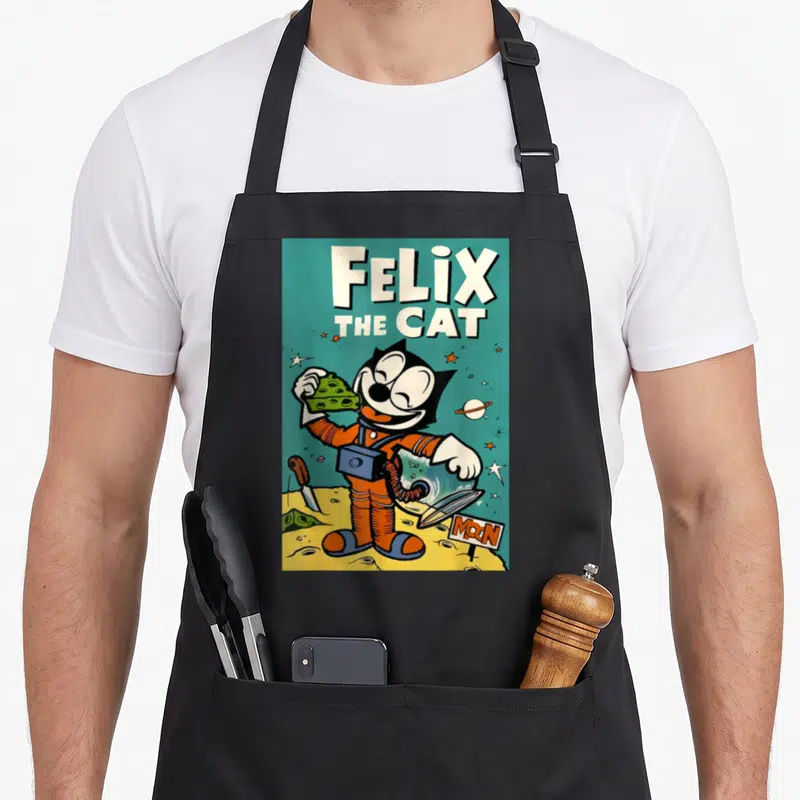 Tablier de cuisine noir avec Felix the Cat en astronaute tenant du fromage vert sur fond lunaire rétro.