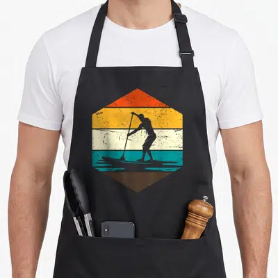 Tablier de cuisine noir avec illustration hexagonale retro d'un homme en stand up paddle sur bandes colorées.