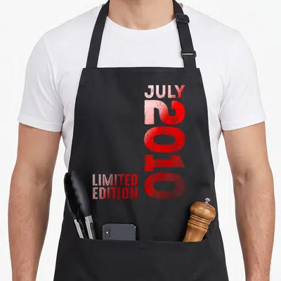 Tablier de cuisine noir avec l'inscription verticale Juillet 2010 en lettres rouges et Limited Edition en bas à gauche.