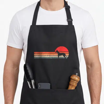 Tablier de cuisine noir avec silhouette de lévrier espagnol sur fond de soleil couchant rayé orange et turquoise.