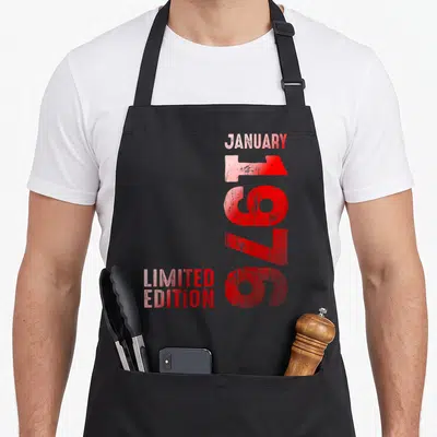 Tablier de cuisine noir avec inscription verticale rouge Janvier 1976 et Limited Edition en bas à gauche.