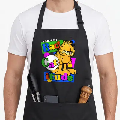 Tablier de cuisine noir avec l'illustration colorée de Garfield et le texte I Like My Bad Catitude en style rétro.