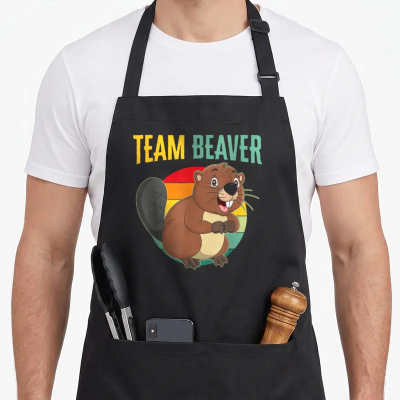 Tablier de cuisine noir avec illustration colorée d'un castor souriant et texte Team Beaver sur fond arc-en-ciel rétro.