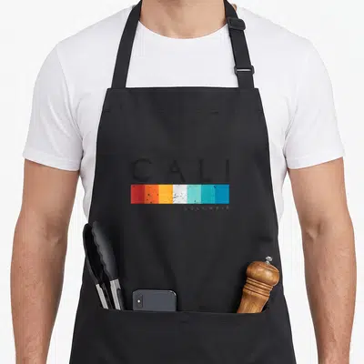 Tablier de cuisine noir avec l'inscription Cali Colombia et une barre de couleurs dégradées rouge orange jaune blanc bleu turquoise.