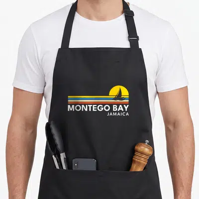 Tablier de cuisine noir avec logo Montego Bay Jamaica voilier et soleil jaune style rétro