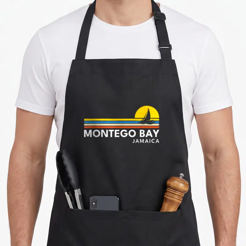 Tablier de cuisine noir avec logo Montego Bay Jamaica voilier et soleil jaune style rétro