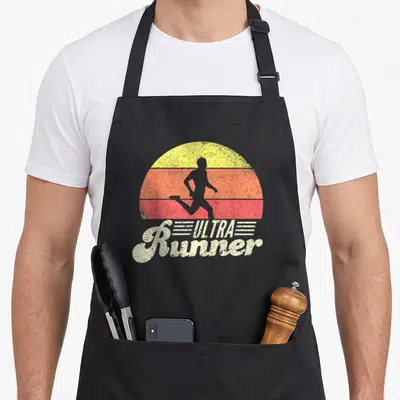 Tablier de cuisine noir avec silhouette de course et texte Ultra Runner Classic sur fond de soleil rétro.