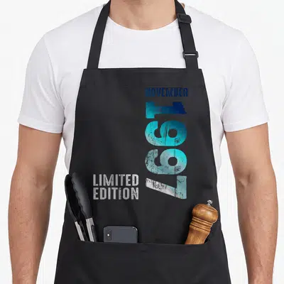 Tablier de cuisine noir avec l inscription Novembre 1997 et Limited Edition en typographie rétro bleue et blanche.