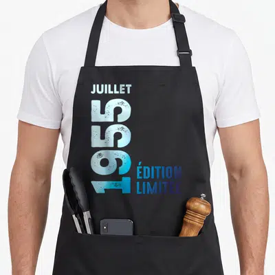 Tablier de cuisine noir avec l'inscription verticale Juillet 1955 et « Édition Limitée » en typographie bleue délavée.