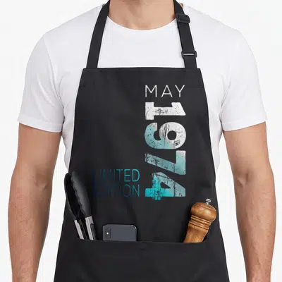 Tablier de cuisine noir avec l'inscription Mai 1974 Limited Edition en typographie dégradée bleue et blanche.