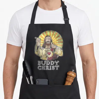Tablier de cuisine noir avec illustration retro de Buddy Christ pointant vers le haut et le pouce levé.