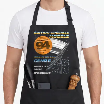 Tablier de cuisine noir avec illustration de balai de windshield et vignette orange portant le numéro 94 ainsi que des textes typographiques rétro.