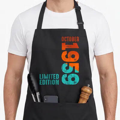 Tablier de cuisine noir avec typographie verticale Octobre 1959 Limited Edition orange et turquoise usée.