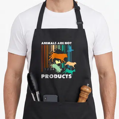 Tablier de cuisine noir avec code-barres multicolores, silhouettes d'animaux et texte Animals Are Not Products en blanc.