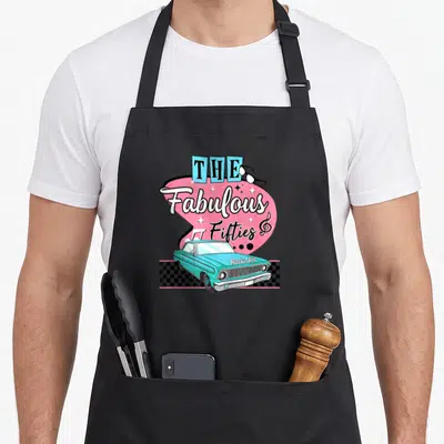 Tablier de cuisine noir avec une voiture turquoise et le texte The Fabulous Fifties sur fond rose.