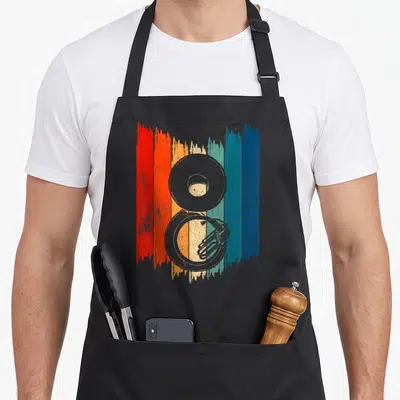 Tablier de cuisine noir avec illustration d'un lecteur de sousaphone rétro sur fond de bandes colorées verticales.