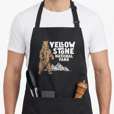 Tablier de cuisine noir avec illustration d'ours grizzly et texte YELLOW STONE NATIONAL PARK en blanc et orange.