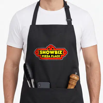 Tablier de cuisine noir avec l'enseigne Showbiz Pizza Place en rouge, jaune et blanc.