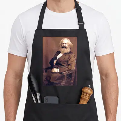 Tablier de cuisine noir avec portrait vintage de Karl Marx assis sur un fauteuil en bois.
