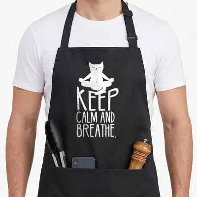 Tablier de cuisine noir avec illustration blanche d'un chat en méditation et texteKeep Calm and Breathe.