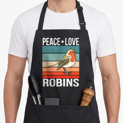 Tablier de cuisine noir avec illustration de rouge-gorge et texte PEACE LOVE ROBINS sur fond de bandes horizontales colorées.