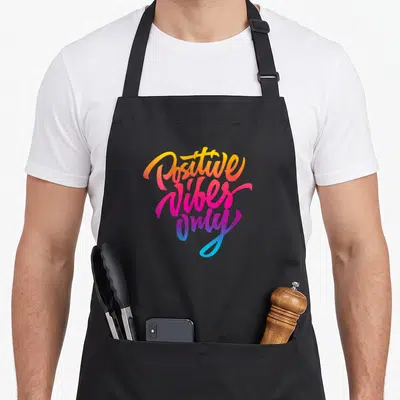 Tablier de cuisine noir avec l'inscription Positive Only en lettres colorées style rétro.